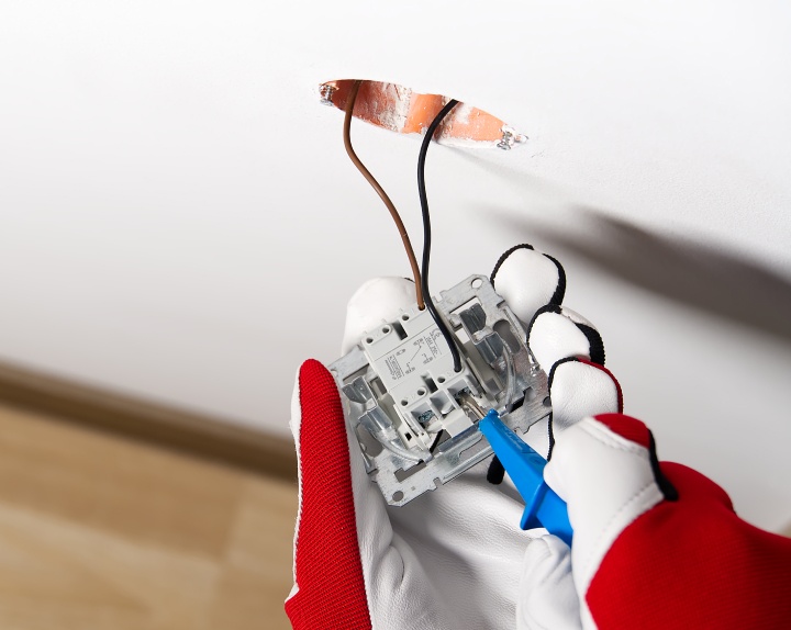 electrician installing light switch on painted wall with screwdriver bay shore ny